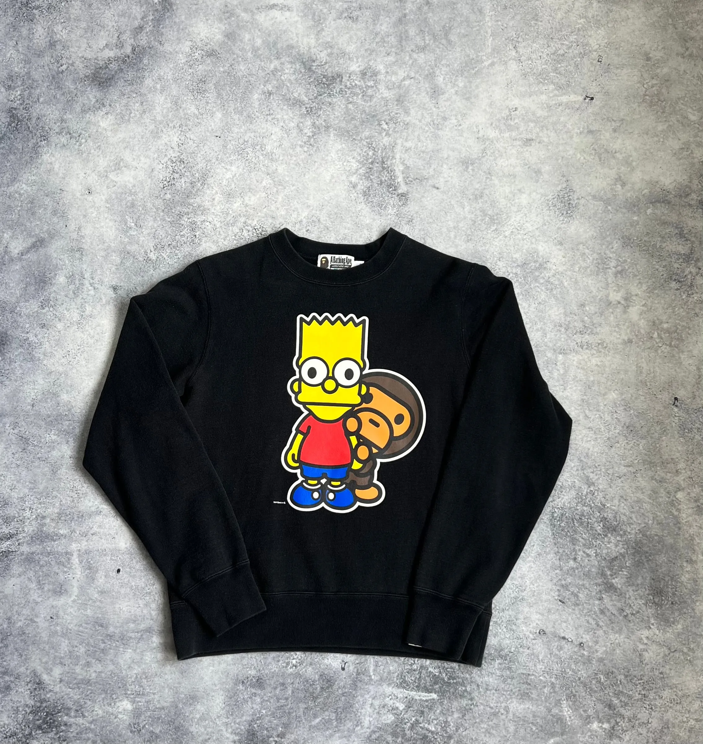 Bape x the Simpsons baby Milo behind Bart black sweatshirt